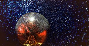 Shining disco ball with colorful reflections in a dark, starry background.